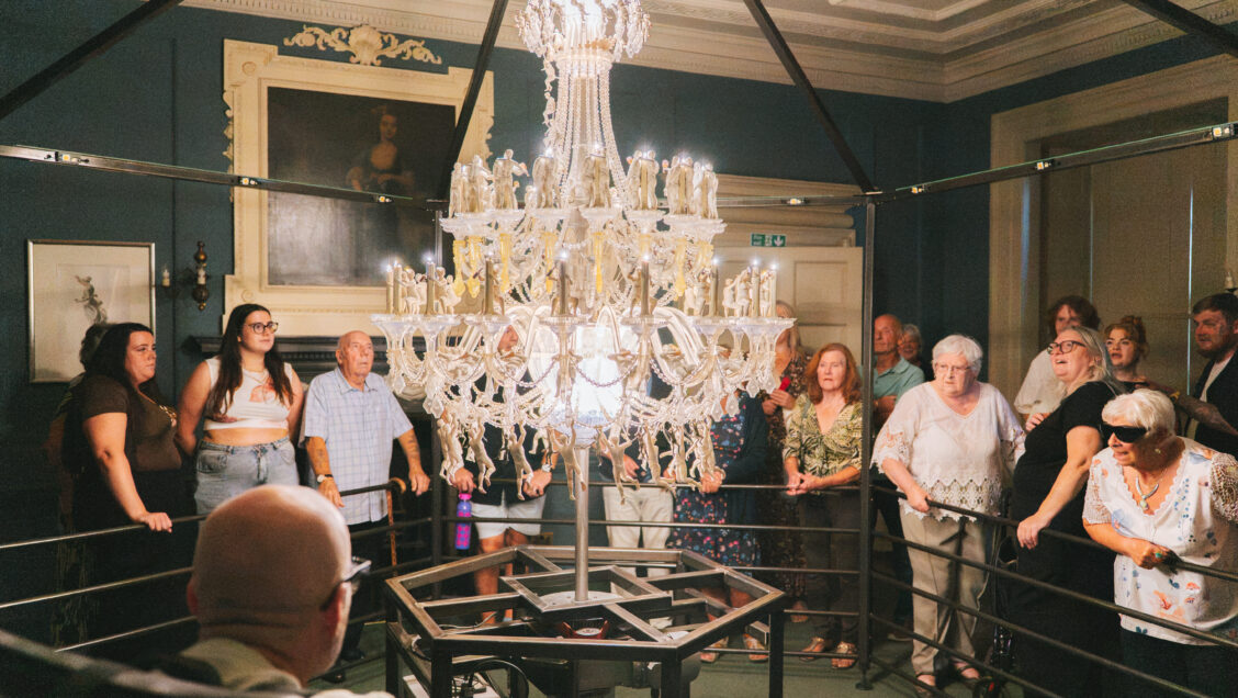 A group watch a chandelier art installation as it spins