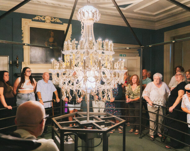 A group watch a chandelier art installation as it spins