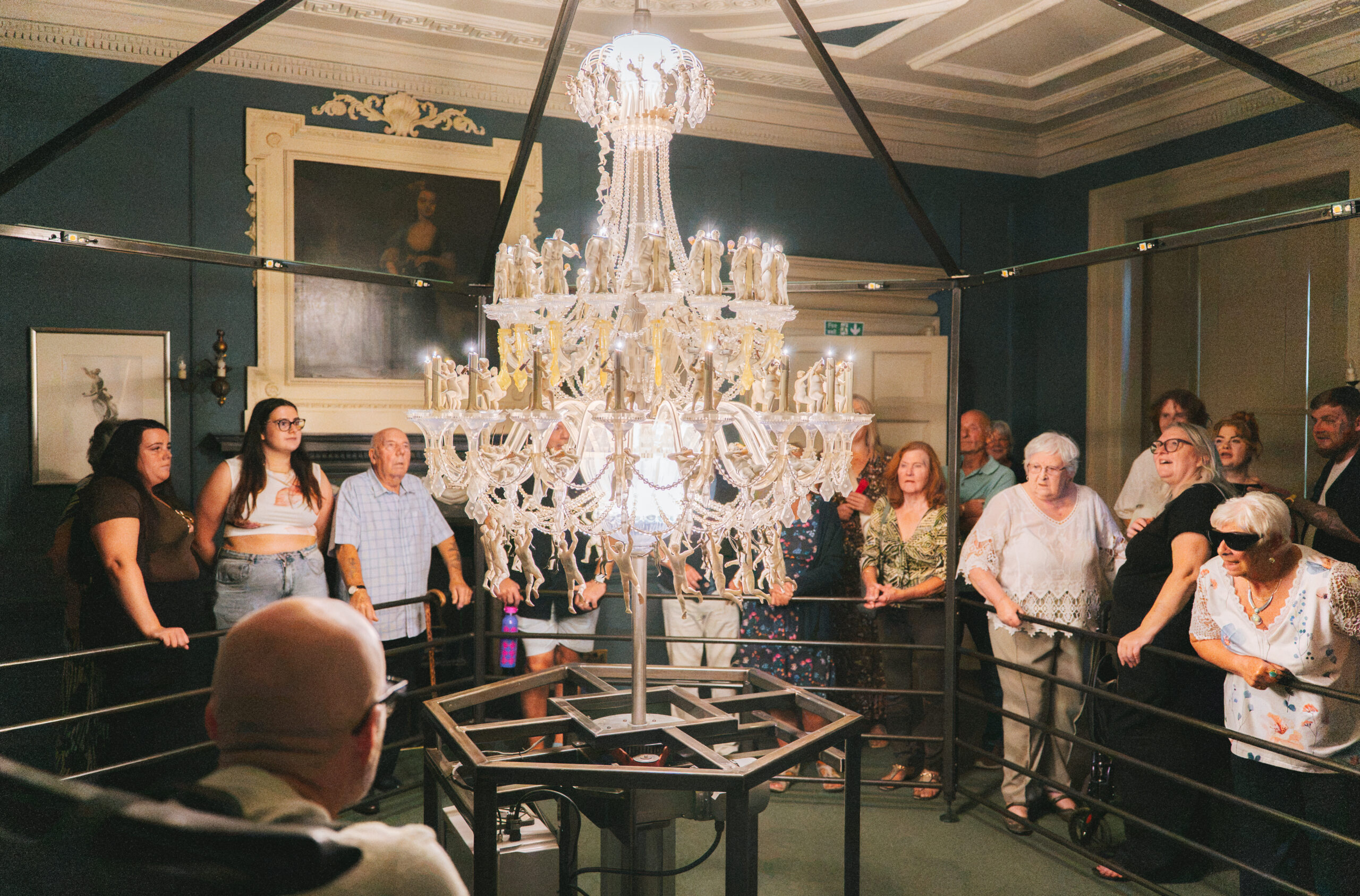 A group watch a chandelier art installation as it spins
