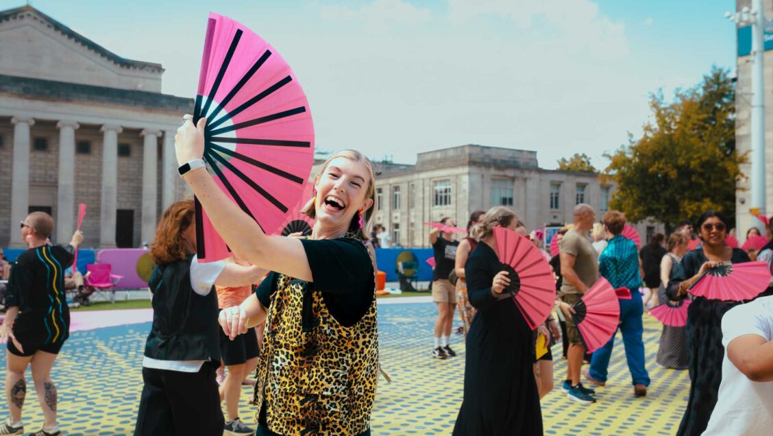 A group dancing with pink fans
