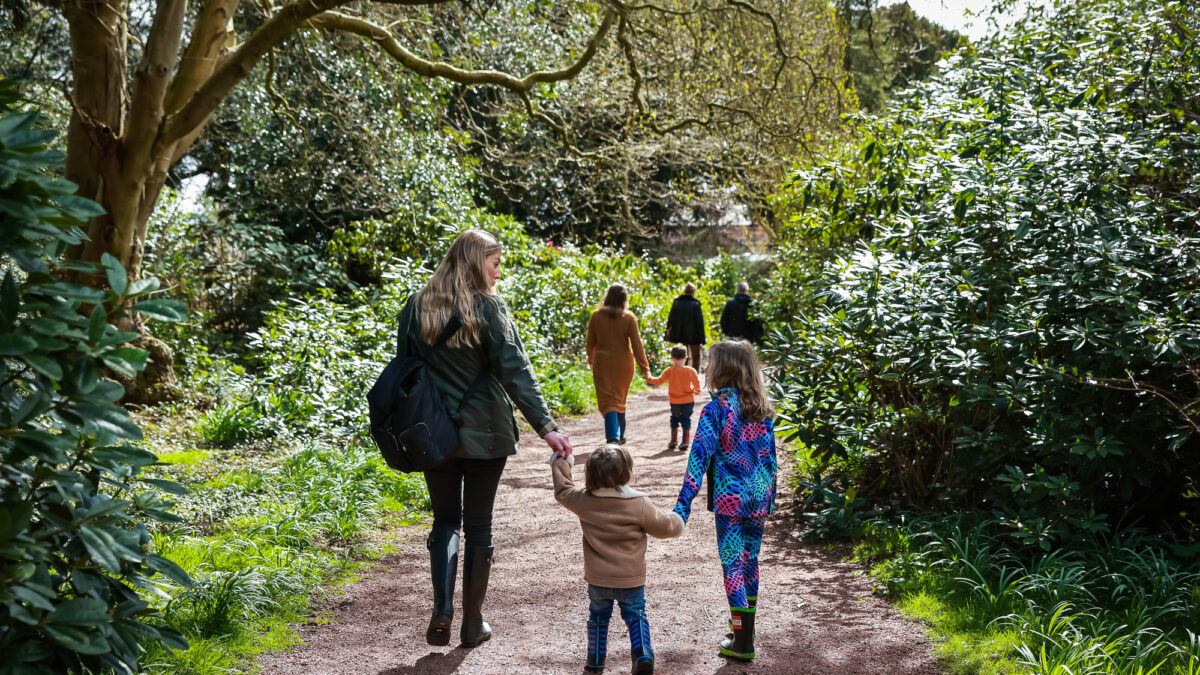 A family exploring the gardens holding hands
