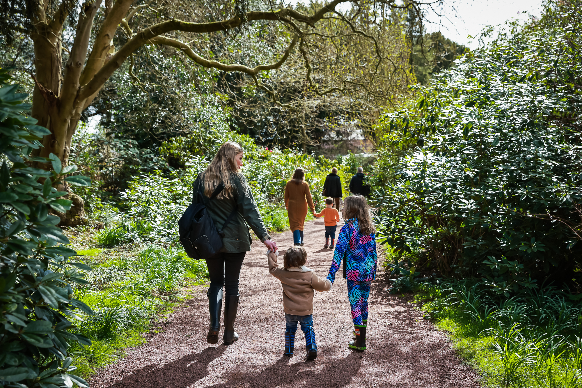 A family exploring the gardens holding hands